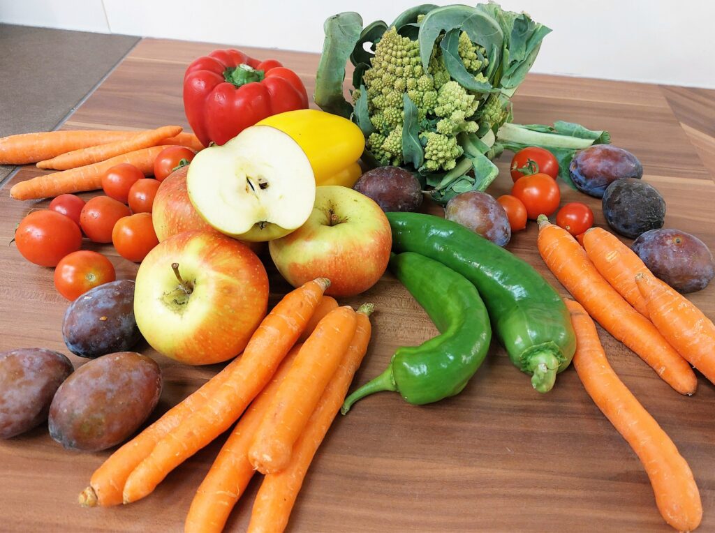 Frisches Gemüse und Obst auf einer Küchenarbeitsplatte ansprechend arrangiert.